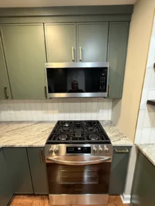 Green kitchen cabinets, stone countertops and stainless steel range