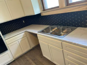 Light kitchen countertop with a double sink and blue tile backsplash