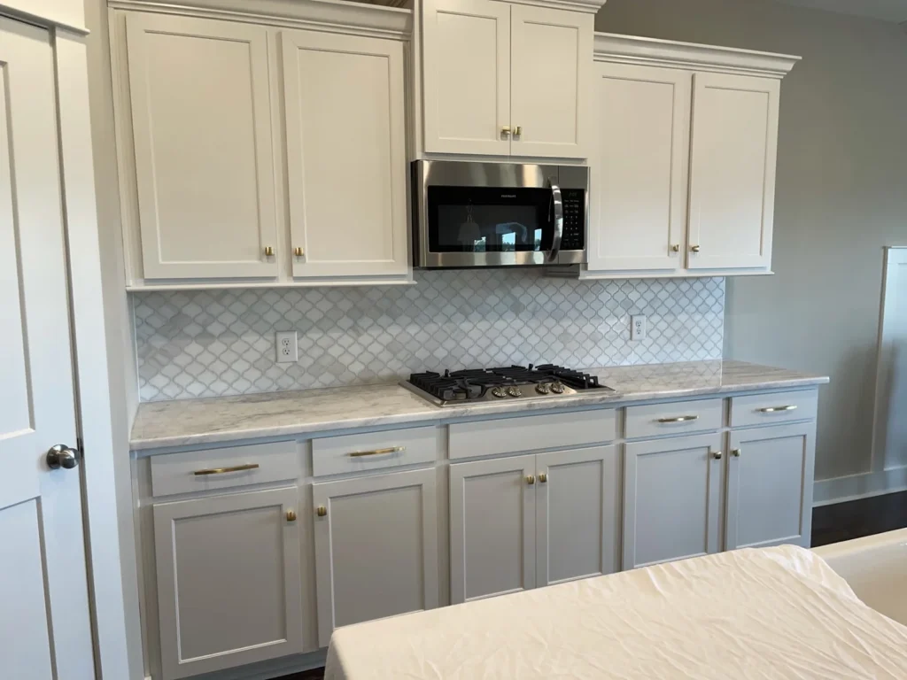 White kitchen cabinets, patterned backsplash and a kitchen island