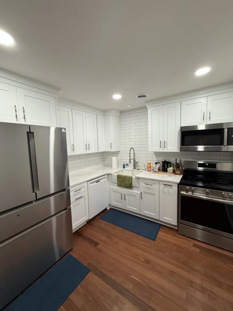 White kitchen cabinetry with recessed lighting and wood-look flooring