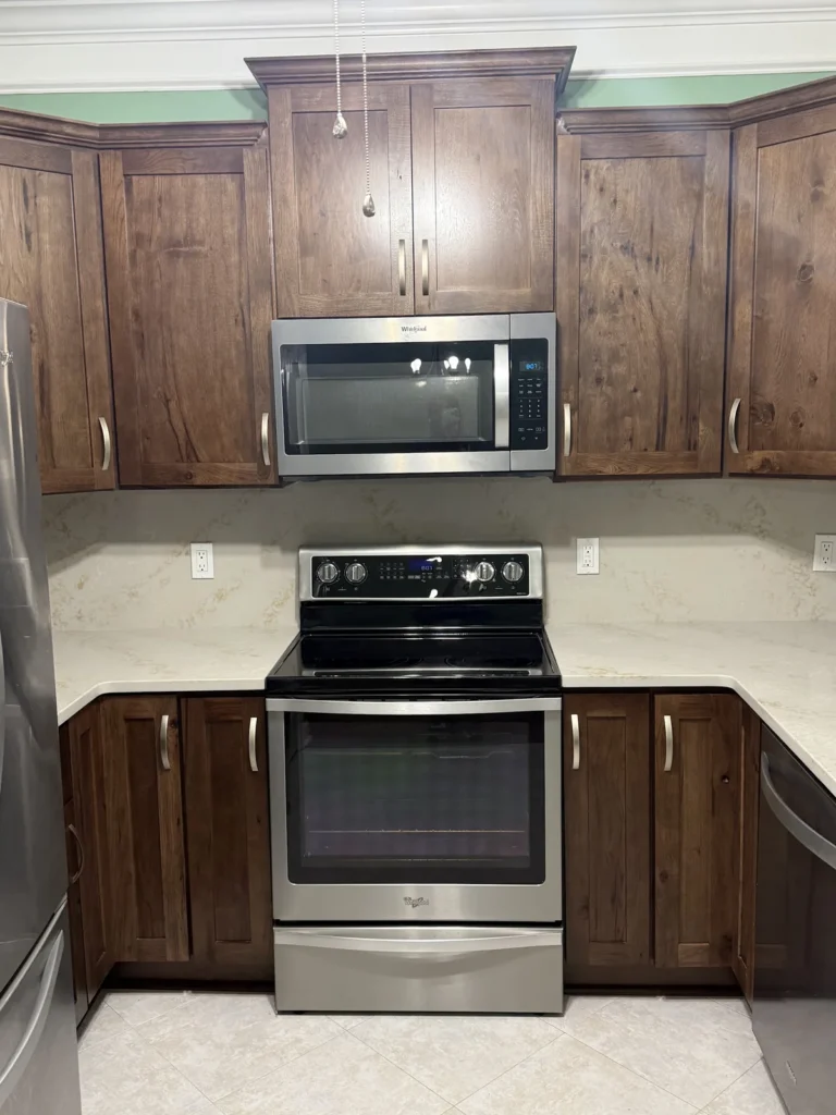 Wood kitchen cabinets with a light countertop and stainless steel appliances